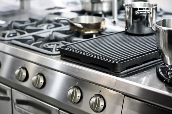 Part of a modern kitchen in the restaurant or hotel with professional equipments - steel gas cooker, pots and pans ( low DOF)